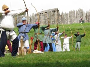 A row of archers loose their arrows at a target
